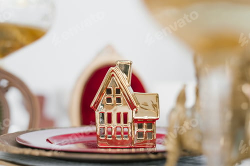 Preview: Festive Christmas dinner service. Golden souvenir house on a dinner plate on the table