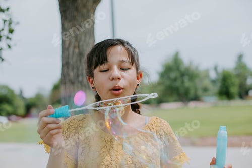 Preview: Young girl blowing bubbles at the park in summer