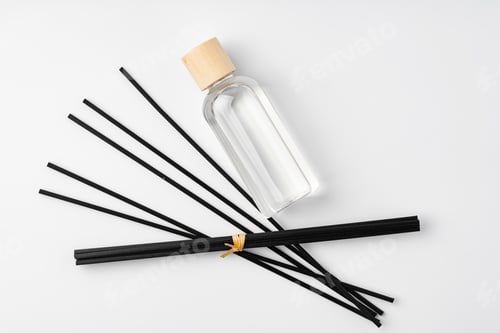 Preview: A minimalist display of essential oil and black diffuser sticks on a clean white background