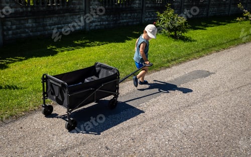 Preview: Child pulls a four-wheel folding wagon with toys and accessories during a tourist trip