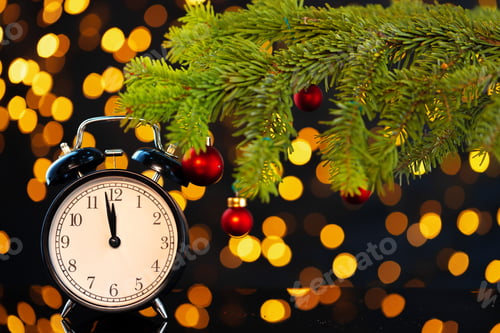Preview: New Year eve concept with alarm clock against blurred garland