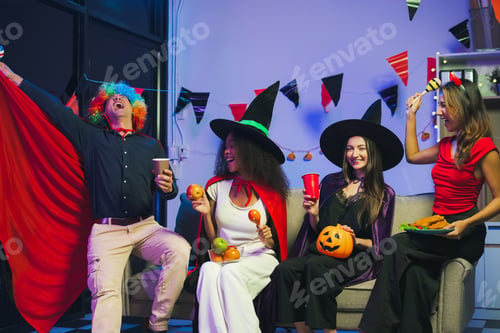 Preview: Dinner and group of people celebrating together at Halloween party.