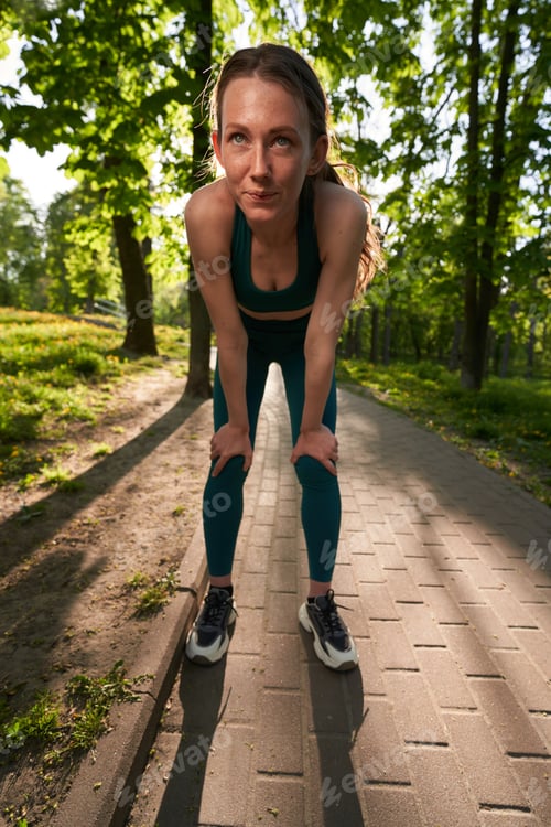 Preview: Active woman having break while jogging in nature