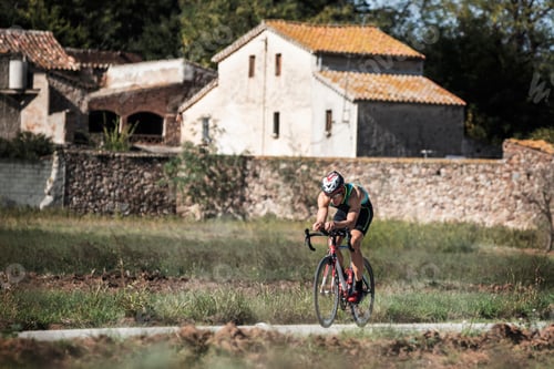Preview: Man riding a bike in a country road with farmhouses around