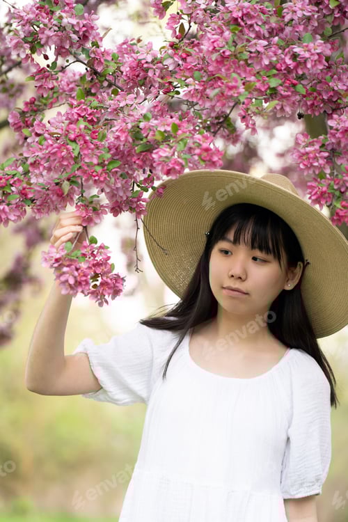 Preview: Portrait of a girl teen smiling under pink flower tree