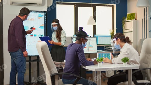 Preview: Multi ethinc women with protection masks analysing annual reports
