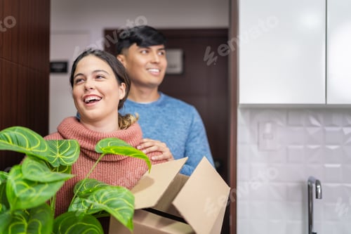 Preview: Happy latin couple moving into new apartment carrying boxes