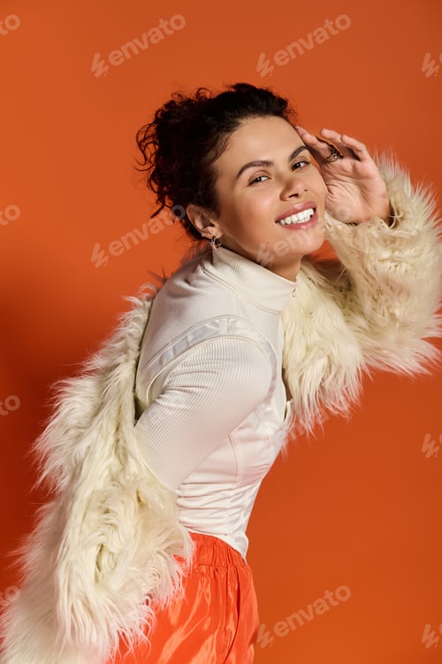 Preview: Young fashionable woman shines with confidence in vibrant orange backdrop