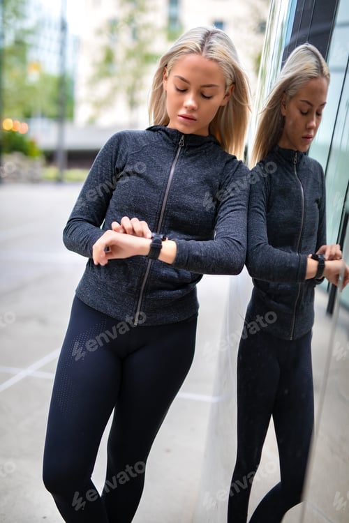 Preview: Woman using fitness smart watch device before running in city