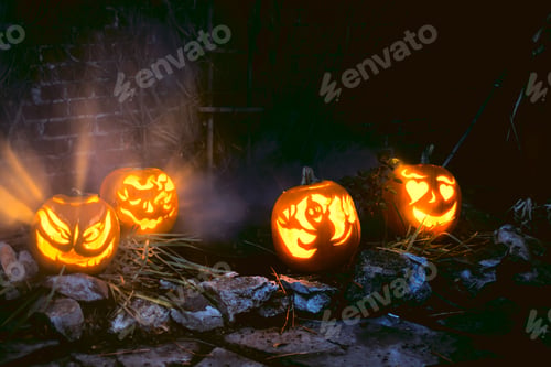 Preview: Halloween Jack O’lantern pumpkins lit up with spooky carvings in garden background