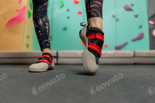 Preview: close-up of girl's legs on a climbing wall wearing professional climbing shoes