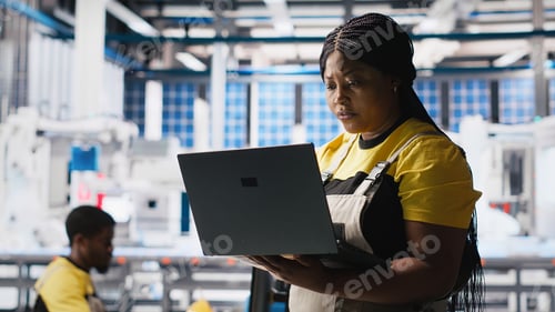 Preview: Woman engineer in photovoltaics factory uses tracking software on laptop