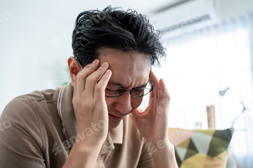 Preview: Asian mature upset depressed man sitting alone in living room at home.