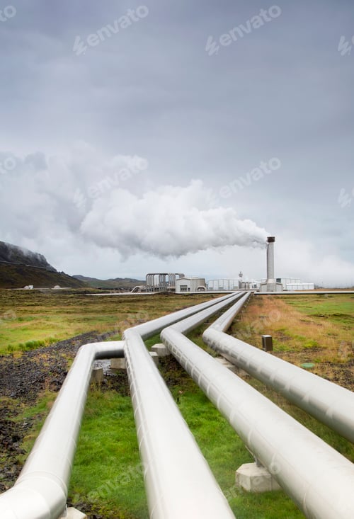 Preview: View along pipelines, factory with smoking chimney stack in the distance.