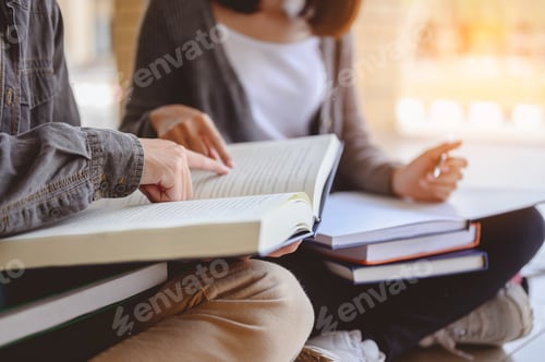 Preview: Two students are sitting on the floor reading books to education. Study for test preparation