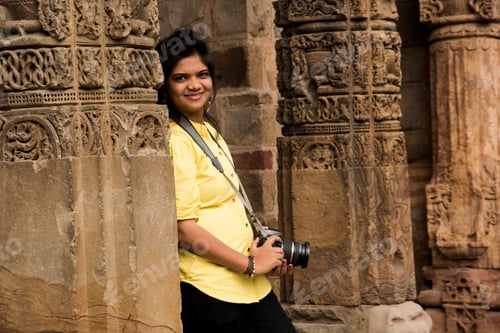 Preview: Young woman photographer with DSLR camera at Qutub Minar , Delhi, India.