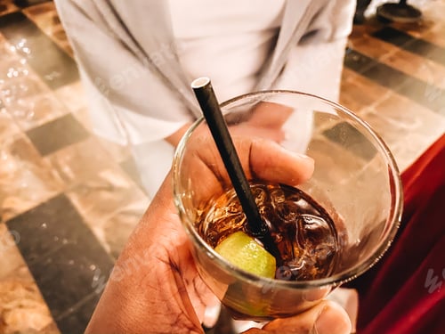 Visualização: homem afro-americano na festa de Natal segurando uma bebida de rum e coca