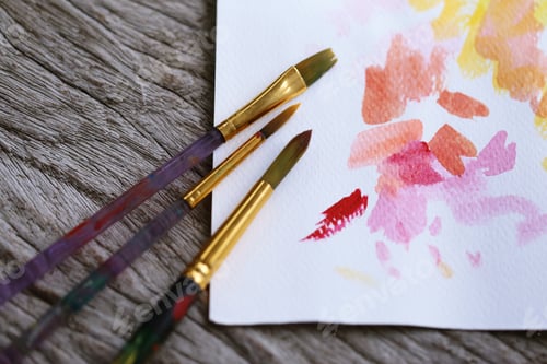 Preview: Paintbrushes and watercolor painting on rustic wooden surface