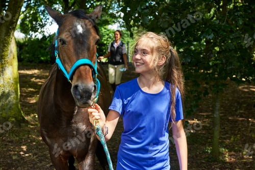 Preview: Girl holding lead rope looking at horse smiling