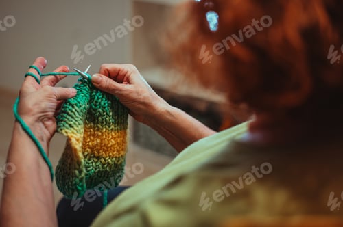 Preview: Close up of the hands of a senior woman knitting at home.