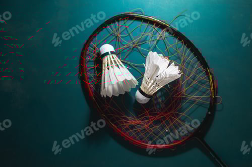 Preview: badminton shuttlecock with badminton racket breaking strings on court rubber floor.