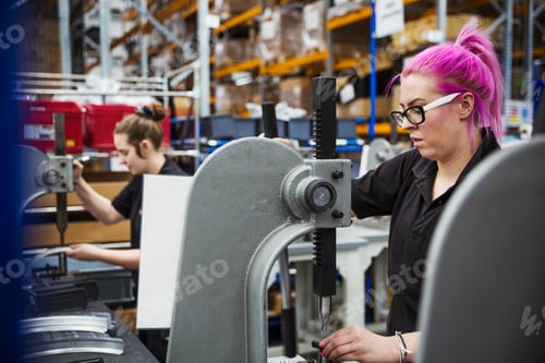 Preview: A young woman with pink hair, a female factory worker using a hole punching machine, working to