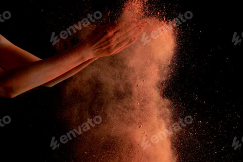 Preview: cropped view of female hands with orange colorful holi paint burst on black background