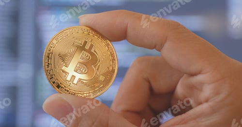 Preview: Hand holding bitcoin over the computer screen