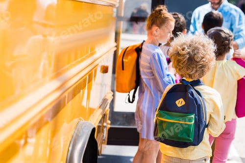 Preview: rear view of group of pupils near school bus