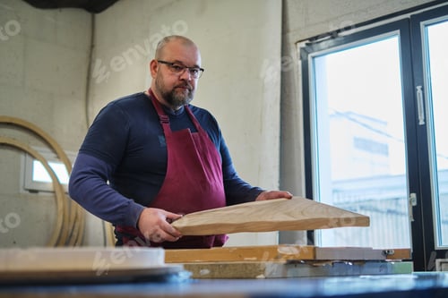 Preview: A masterful craftsman inspects a wooden board with care. His expertise shines in the meticulous