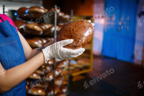 Preview: Girl baker works in a bakery. Fresh crispy bread close up