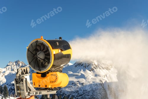 Preview: Operating artificial snow cannon near piste making snowy powder.Ski lift ropeway on hilghland alpine