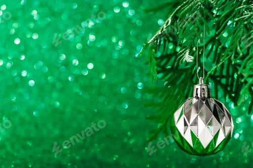 Preview: Silver Christmas ball on shiny green background. New Year concept