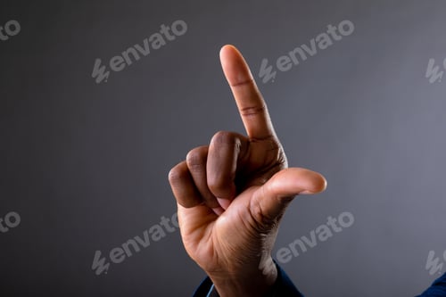 Preview: Mid section of african american businessman touching invisible screen against grey background
