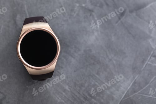 Preview: Trendy smart watch on grey stone table, top view. Space for text