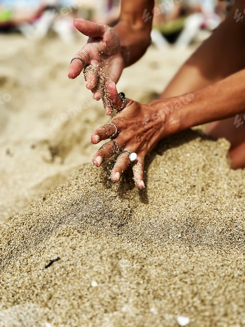 Preview: Female Hands With Pastel Manicure, Fashionable Jewelry Rings Holding White Sand on Tropical Beach