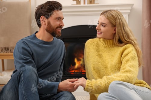Preview: Lovely couple spending time together near fireplace indoors