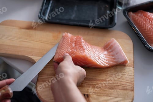 Preview: Hand chef using knife slice raw salmon on chopping board