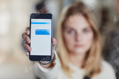Preview: Closeup shot of a university student holding up a cellphone with a rude text message