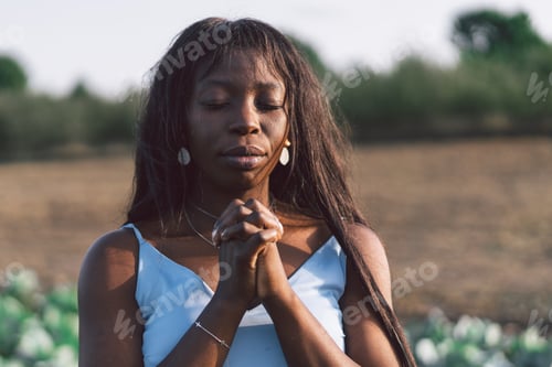 Preview: Afro Girl closed her eyes, praying in a outdoors. Hands folded in prayer concept for faith