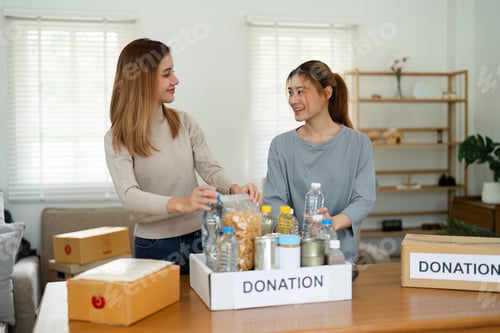 Vista previa: charity, donation and volunteering concept. Volunteer prepare foodstuff box containing food to
