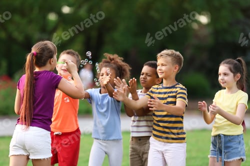 Preview: Cute little children playing with soap bubbles in park