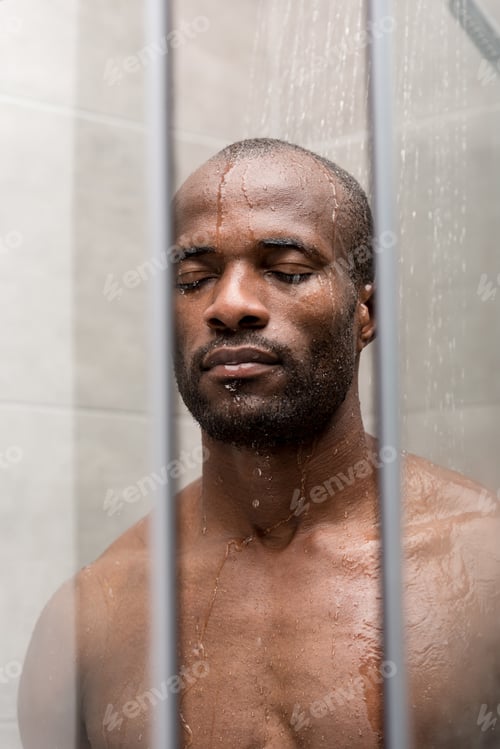 Preview: handsome young african american man standing with closed eyes in shower