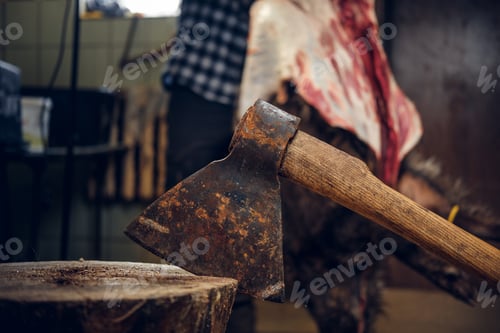 Preview: Close up image of axe over bearded butcher on background.