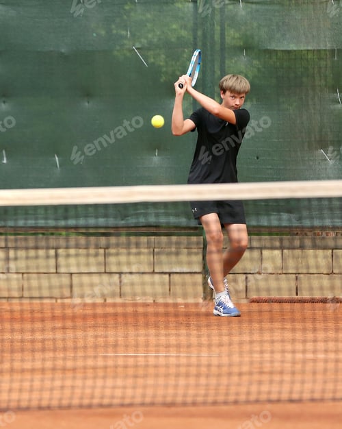 Preview: handsome boy teenager fifteen years playing tennis on an open court