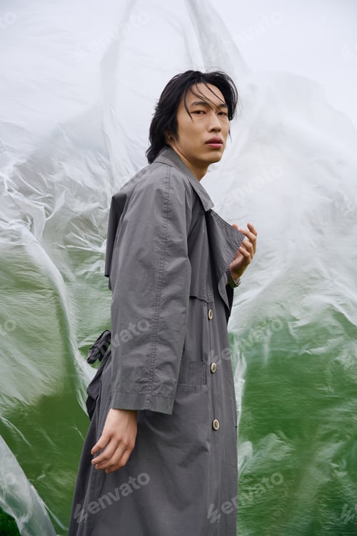 Preview: Stylish young man in grey trench coat enjoying a peaceful park day