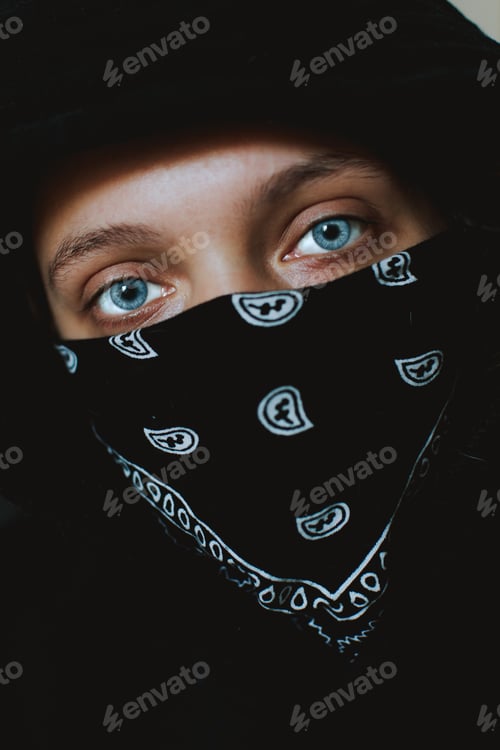Preview: Vertical closeup shot of a blue eyes Caucasian person covering the mouth with black bandana
