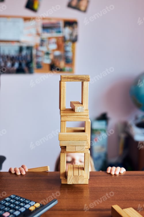 Preview: Little girl preschooler playing with wooden blocks toy building a tower. Concept of building a house