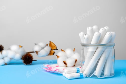 Preview: Female medical tampons and cotton flower on blue paper background