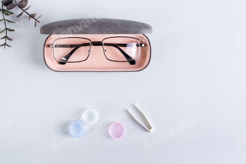 Preview: A case with glasses, an open container with contact lenses and tweezers. Top view.